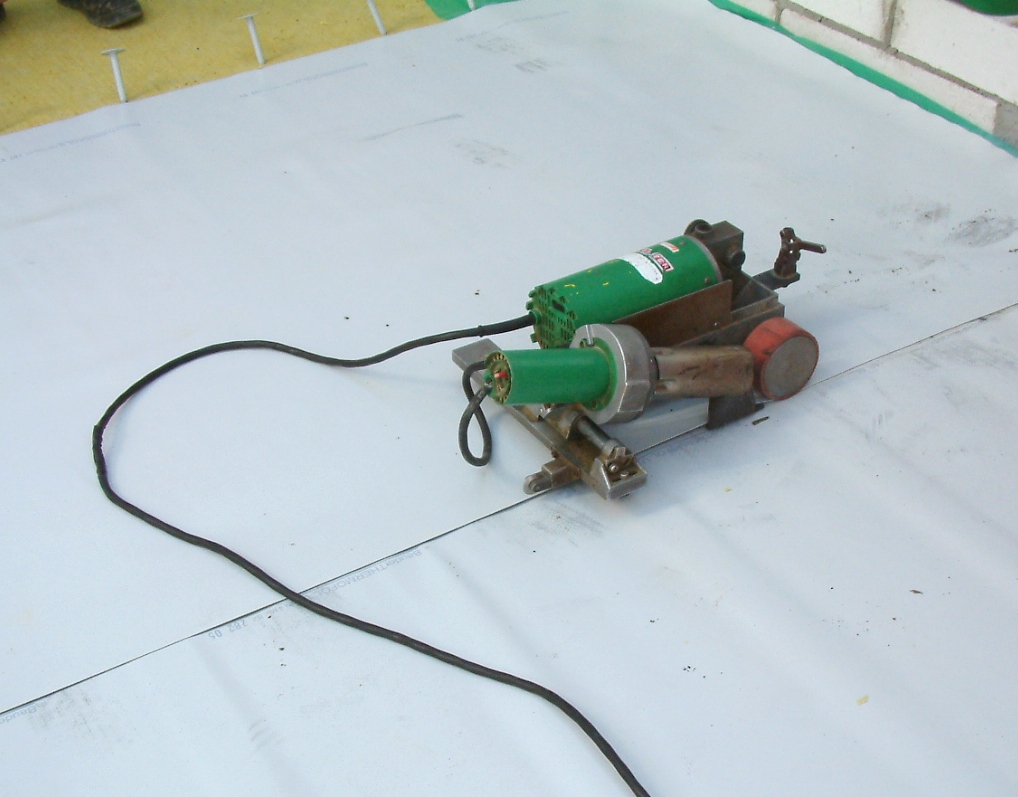Reference photograph of membrane-sealing equipment on a light-colored flat roof