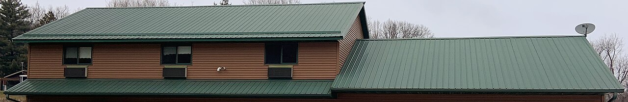 Green ribbed metal roofing on connected gabled roof sections
