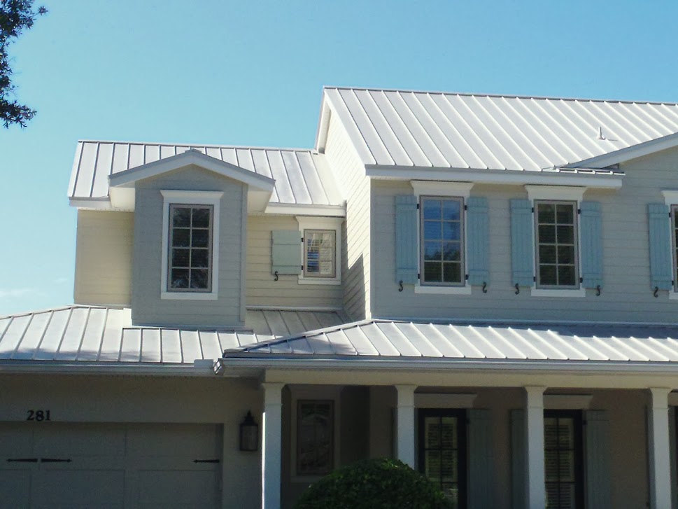 Light-colored house with silver standing-seam metal roofing over gables and porches