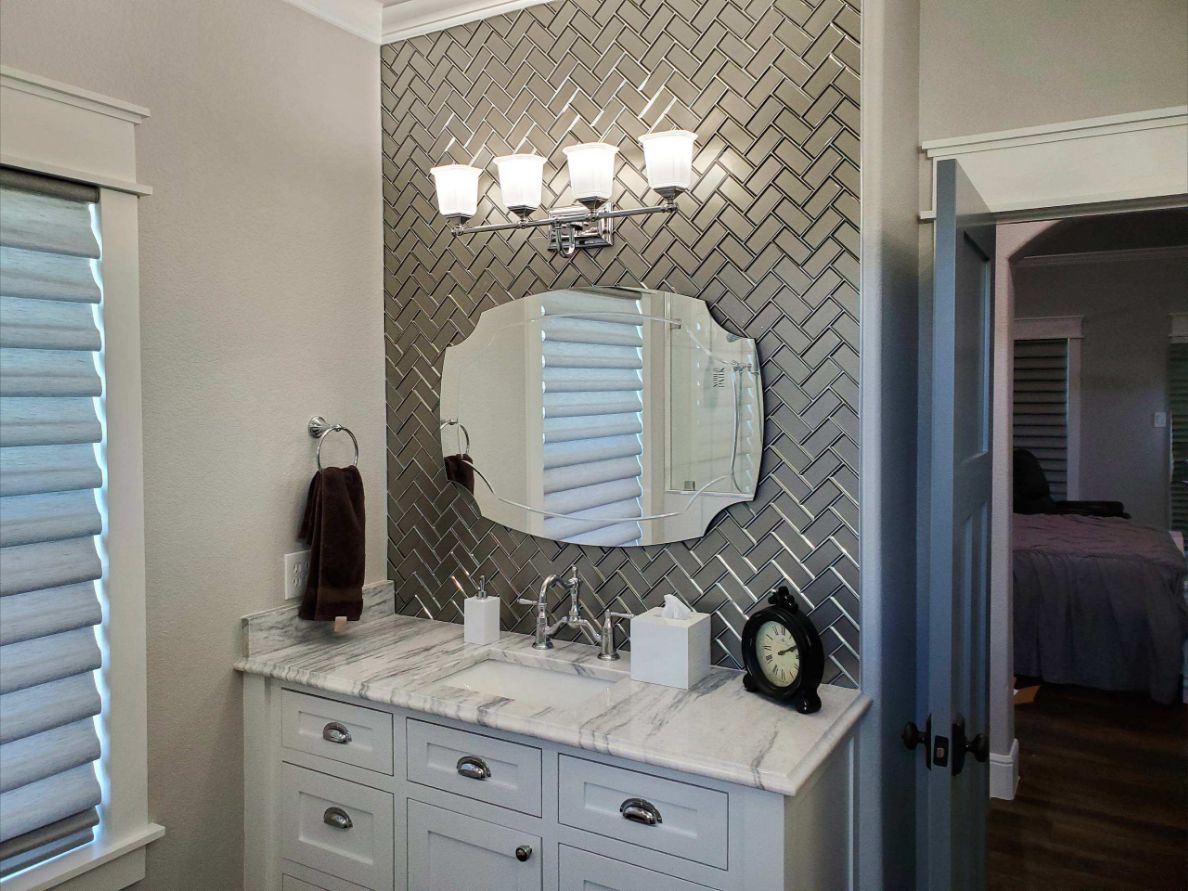 Bathroom vanity with marble countertop, herringbone tile and chrome lighting