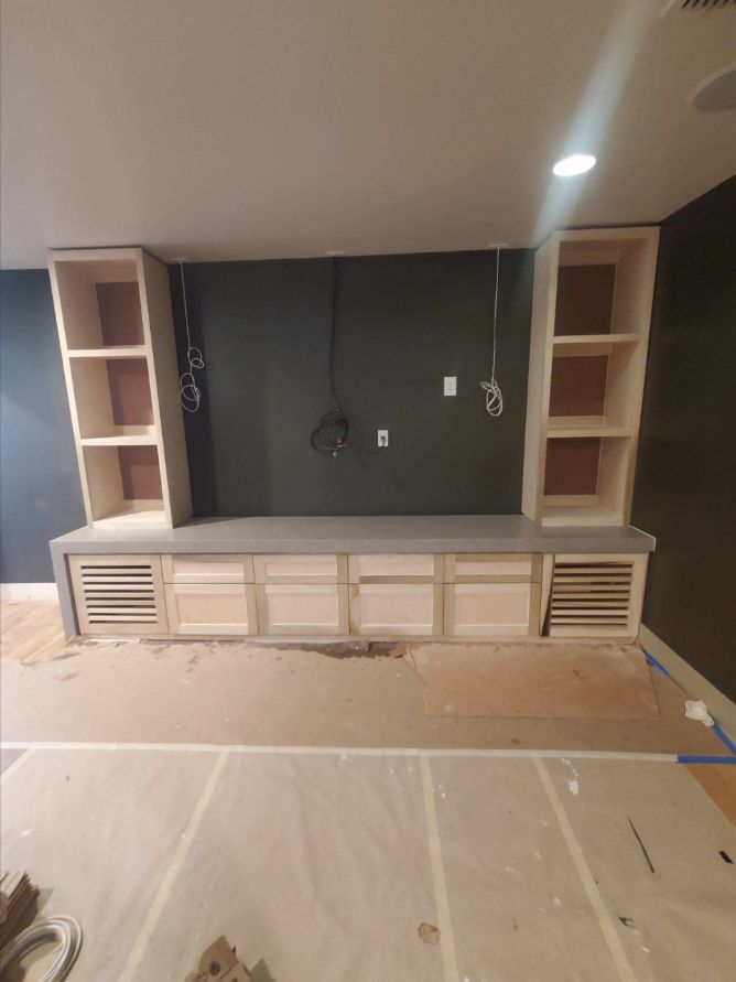 Built-in entertainment center with base cabinets, vented doors and bookcase towers during installation