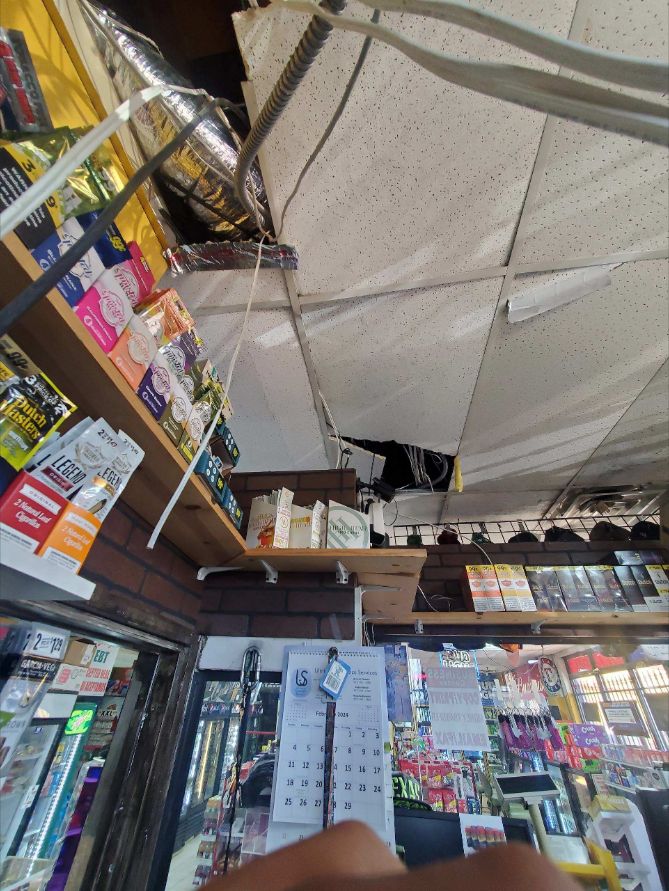 Opened commercial ceiling showing damaged tiles, wiring and ductwork during inspection