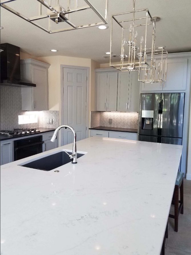 White and gray kitchen remodel with oversized quartz island and pendant lighting