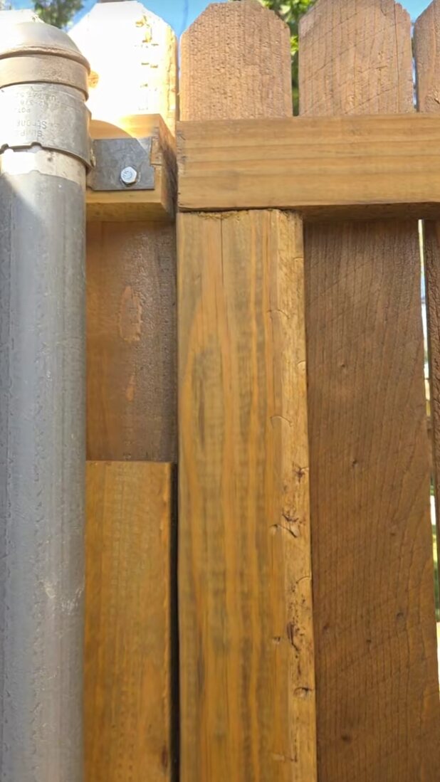 Close-up of heavy-duty galvanized fence post and wood framing hardware