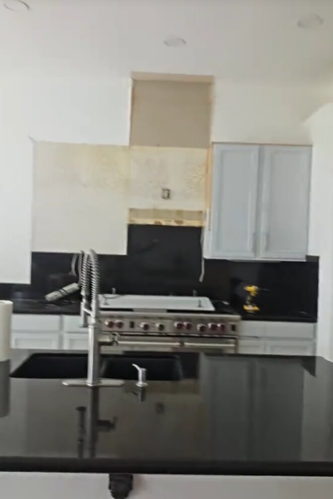 Kitchen remodel with black countertops, white cabinets and commercial-style range